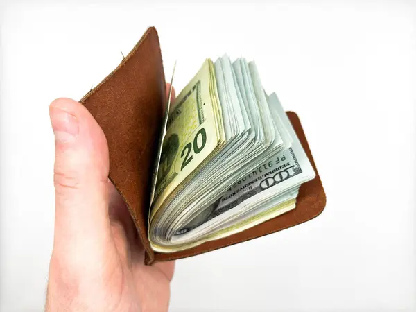 Deri kahverengi para tutucu elinde nakit dolarlarla beyaz arka planda 100 dolarlık banknotla görüntünün merkezinde yer alıyor. Yüksek kalite fotoğraf