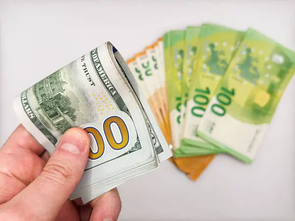 Beyaz arka planda avroya karşı 100 dolarlık banknot tutan bir erkek. Yüksek kalite fotoğraf