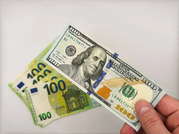 Görüntünün sol tarafındaki erkek, avroya karşı 100 dolarlık banknot tutuyor. Beyaz arka planda ABD 'nin Avrupa' ya karşı üstünlüğünü gösteriyor. Yüksek kalite fotoğraf
