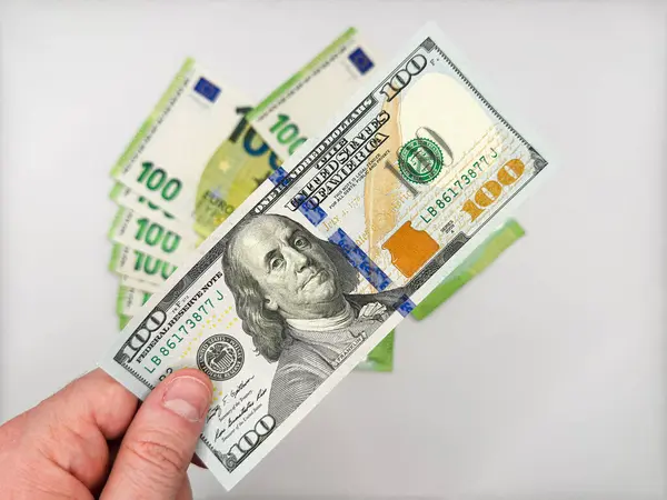 Avro karşısında 100 dolarlık banknot tutan erkek, beyaz arka planda avroya karşı dolar üstünlüğünü gösteriyor. Yüksek kalite fotoğraf