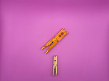 Modern turuncu plastik elbise mandalına karşı eski ahşap kahverengi elbise askısı. Mor arka plan görüntüsüne odaklanmış, gereksiz nesnelerin üst görünümü yok. Yüksek kalite fotoğraf