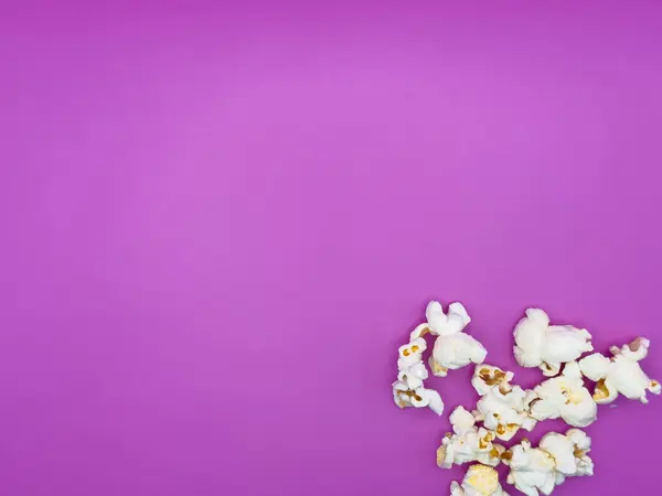 Mor arka planda beyaz tuzlu patlamış mısır. Sağ alt köşeden yukarıdan görünüyor. Yüksek kalite fotoğraf