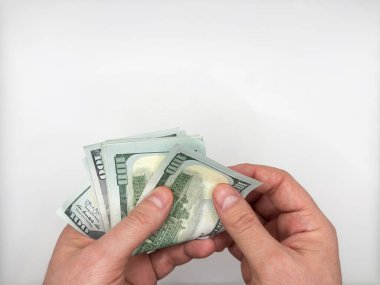 Erkek eller 100 dolarlık banknotları açık tutuyor ve beyaz arka planda iki elle sayıyor. Yüksek kalite fotoğraf
