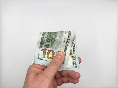 Adam 100 dolarlık banknotları kapalı tutuyor ve tek eliyle beyaz arka planda şifreli para alıyor. Yüksek kalite fotoğraf