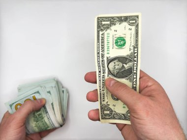 Beyaz erkek eller, arka plandaki beyaz arka planda tuttuğu bir yığın doların vergisini ödemek için bir dolar tutuyor. Yüksek kalite fotoğraf