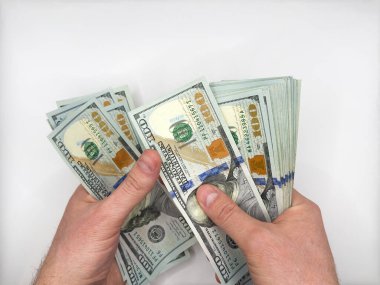 Elinde 100 dolarlık banknotlar tutan ve iki eliyle beyaz arka plan manzaralı banknotları sayan adam. Yüksek kalite fotoğraf