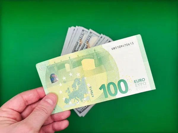 Aşağıdan parlak yeşil arka plan manzaralı 100 avroluk banknotları tutan bir erkek. Yüksek kalite fotoğraf