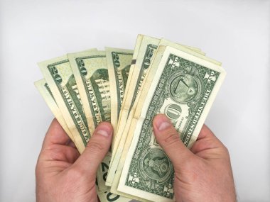 Beyaz erkek eller, görüntünün ortasındaki beyaz arka planda bir yığın dolar tutuyor ve yüzükoyun 20 dolar ediyor. Yüksek kalite fotoğraf