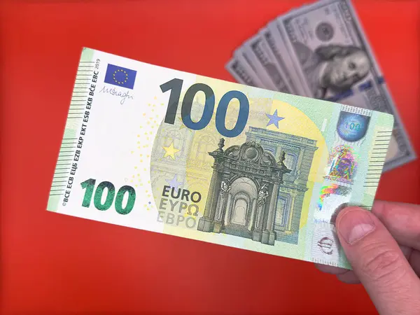 100 avroluk banknota karşılık 100 avroluk banknot tutan erkek, Avrupa 'nın parlak kırmızı arka plan manzarasında ekonomideki ABD' den daha güçlü olduğunu gösteriyor. Yüksek kalite fotoğraf