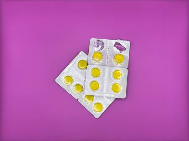 Yeni gümüş bir pakette parlak sarı tabletler ve görüntünün ortasında parlak mor bir zemin üzerinde kullanılmış bir paket dikey olarak yerleştirilmiş iki paket var. Yüksek kalite fotoğraf