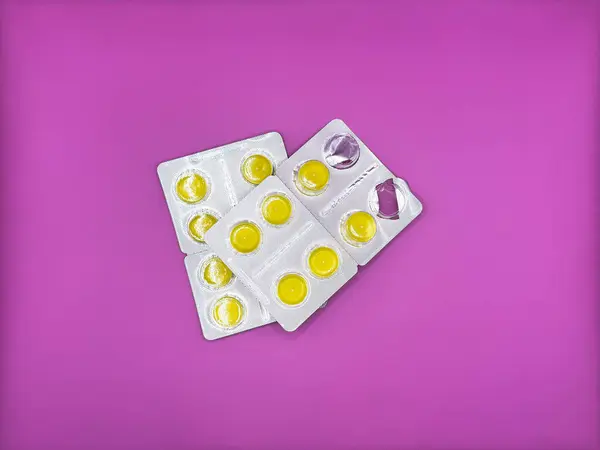 Yeni gümüş bir pakette parlak sarı tabletler ve virüsün tedavisinde kullanılan bir paket. Görüntünün merkezindeki parlak mor arka planda. Yüksek kalite fotoğraf
