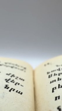 Sarı sayfaları dikey pozisyonda olan bir kitabın makro görüntüsü, kamera beyaz arkaplanda yavaş çekimde harflere çok yakındır. Yüksek kalite 4k görüntü