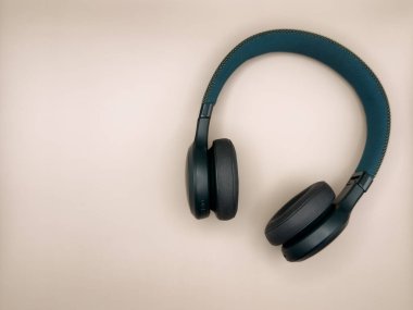 Yumuşak kulaklıklı büyük yeşil kulaklıklar ve yumuşak bir saç bandı ve yan kulaklıklar bej arka planda görüntünün sağ tarafında yatar. Yüksek kalite fotoğraf