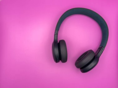Yumuşak kulaklıklı yeşil kulaklıklar ve yumuşak bir saç bandı pembe arka planda görüntünün sağ tarafında duruyor. Yüksek kalite fotoğraf