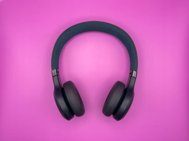 Yumuşak kulaklıklı, yeşil plastikten yapılmış büyük kulaklıklar ve pembe arka plandaki görüntünün ortasında yumuşak bir saç bandı var. Yüksek kalite fotoğraf
