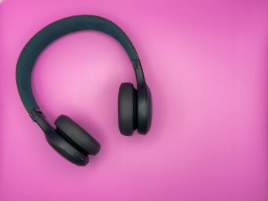 Yumuşak kulaklıklı büyük yeşil kulaklıklar ve pembe arka planda görüntünün sol tarafında yumuşak bir saç bandı var. Yüksek kalite fotoğraf