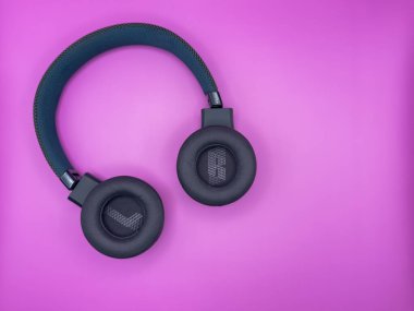 Yumuşak kulaklıklı, L ve R harfli ve yumuşak bantlı yeşil kulaklıklar pembe arkaplanda solda duruyor. Yüksek kalite fotoğraf