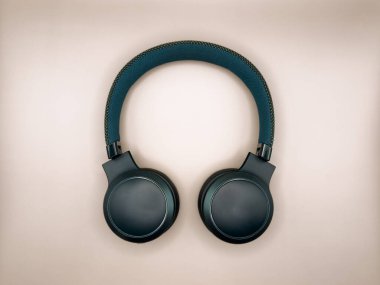 Yumuşak kulaklıklı yeşil kulaklıklar ve açık bej arka planda görüntünün ortasında yumuşak bir saç bandı var. Yüksek kalite fotoğraf