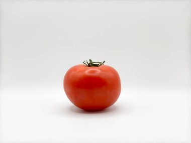 Görüntünün ortasındaki beyaz arkaplanda kırmızı, sulu domates. Gereksiz nesnelerin ön görüntüsü yok. Yüksek kalite fotoğraf