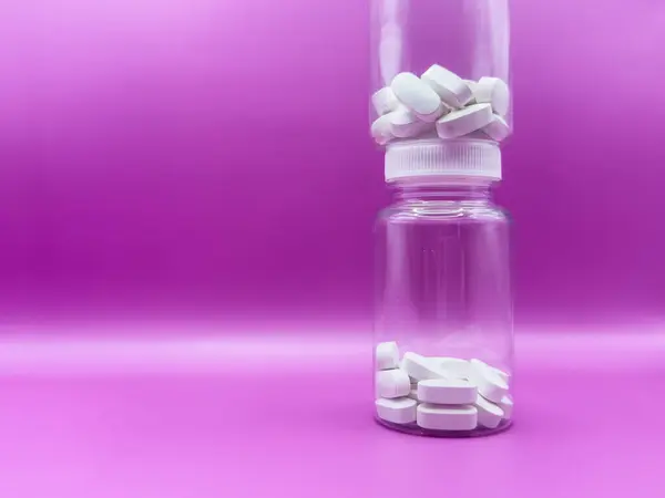 Pembe arka planda, beyaz haplı iki şeffaf kavanoz. Yüksek kalite fotoğraf