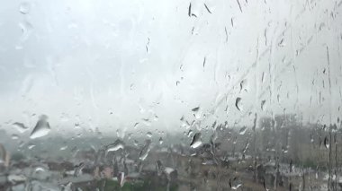 Pencereye yavaşça akan yağmur damlaları akşam şehrini yüksek kalitede görüyor. Yüksek kalite 4k görüntü
