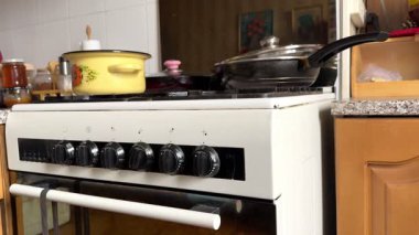 Eski Sovyet mutfağında, üzerinde eski kızartma tavaları olan beyaz bir gaz sobası ve eski sarı bir tencere, ağır çekimde. Yüksek kalite 4k görüntü