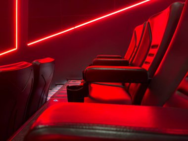 Boş bir sinemada düzgünce düzenlenmiş birkaç sıra kırmızı sinema koltuğunun simetrik görüntüsü klasik ve sürükleyici bir atmosfer yaratıyor. Eğlence, film endüstrisi ve sinema için mükemmel.