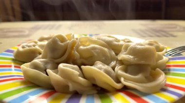 Mutfakta buharlı sıcak ve taze hamur köftesi tabağı yavaş çekimde ve çatalla yan yana. Yüksek kalite 4k görüntü