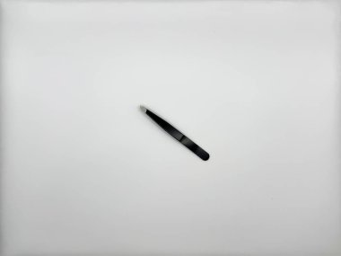 Beyaz arka planda gümüş uçlu siyah metal cımbızlar görüntünün ortasında yatıyordu ve yana doğru dönmüştü. Yüksek kalite fotoğraf