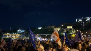 Tiflis, Gürcistan - 9 Mayıs 2025: Tiflis sokaklarında düzenlenen gece gösterisinde AB ve Gürcistan bayrakları taşıyan kalabalık Avrupa entegrasyonunu tutkuyla destekliyor. Yüksek kalite 4k görüntü