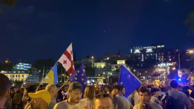 Tiflis, Gürcistan - 9 Mayıs 2025: Tiflis sokaklarında düzenlenen gece gösterisinde AB ve Gürcistan bayrakları taşıyan kalabalık Avrupa entegrasyonunu tutkuyla destekliyor. Yüksek kalite 4k görüntü