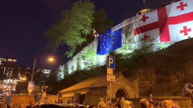 Tiflis, Gürcistan - 9 Mayıs 2025: Tiflis sokaklarında düzenlenen gece gösterisinde AB ve Gürcistan bayrakları taşıyan kalabalık Avrupa entegrasyonunu tutkuyla destekliyor. Yüksek kalite 4k görüntü