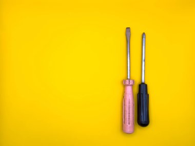 İzole edilmiş sarı arka planda düz bir tornavida. Düz yatıyordu. Üst görünüm, boşluğu kopyala. Yüksek kalite fotoğraf