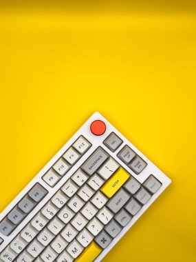 Sarı arka planda beyaz klavye ve parlak kırmızı ve sarı tuşlar. Düz yatıyordu. Üst görünüm, boşluğu kopyala. Reklam. Dikey fotoğraf. Yüksek kalite fotoğraf