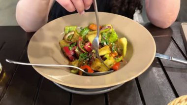 Gümüş çatallı, vejetaryen salatası, sebze salatası ve bej tabaktan vejetaryen salatası yiyen bir kız. Yüksek kalite 4k görüntü