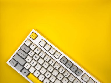 Sarı arka plandaki bilgisayar için mekanik klavye. Gri, beyaz ve sarı renkli anahtar başlık. Düz yatıyordu. Üst görünüm, boşluğu kopyala. Yüksek kalite fotoğraf