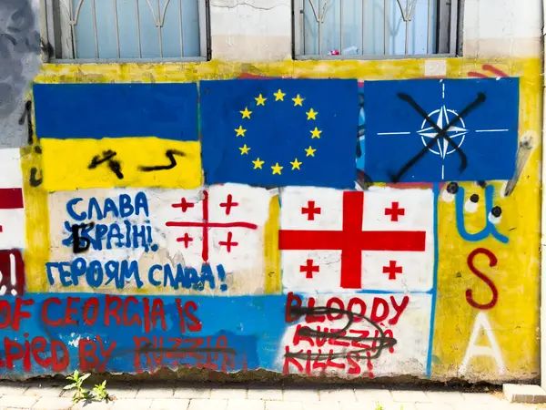 Tiflis, Gürcistan - 09 Mayıs 2025: Tiflis 'te Avrupa Birliği ve NATO üyeliğine destek veren Rus karşıtı graffiti. Rusya 'nın Ukrayna' yı işgali nedeniyle artan gerginlik. AB Ukrayna bayrakları. Yüksek