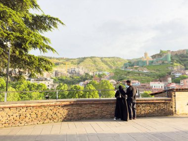 Tiflis, Gürcistan - 10 Mayıs 2025: Tiflis şehrinin önünde duran Müslüman çift, dikiz aynası, fotokopi alanı. Yüksek kalite fotoğraf