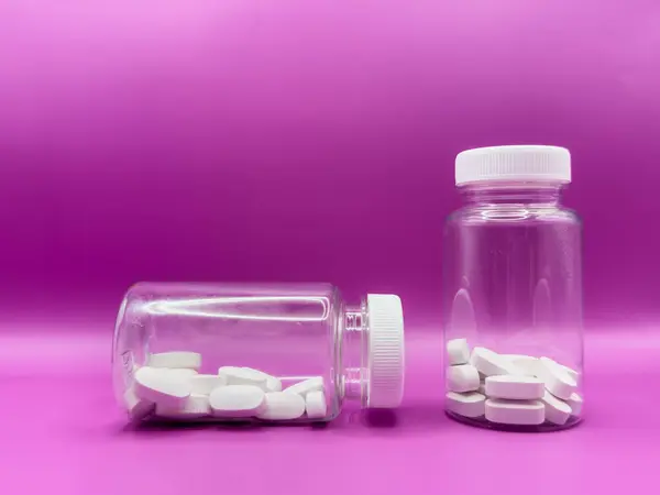 Bir şişe beyaz hap. Pembe arka planda haplar. İlaç stüdyosu beyazın üzerinde izole edilmiş. Yüksek kalite fotoğraf