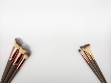 Makyaj fırçaları beyaz arka planda parıltı ve gölge örtüsüyle ayarlanmış minimum modern kozmetik sahne, kopyalama alanı. Yüksek kalite fotoğraf