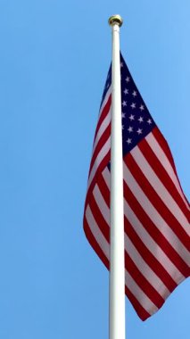 Mavi gökyüzünde büyük bir Amerikan bayrağı dalgalanıyor. Amerikan bayrağı. Amerikan bayrağı. Yüksek 4k kalite video