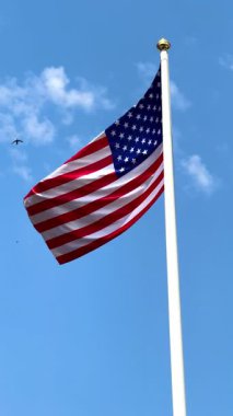 Mavi gökyüzünde büyük bir Amerikan bayrağı dalgalanıyor. Amerikan bayrağı. Amerikan bayrağı. Yüksek 4k kalite video