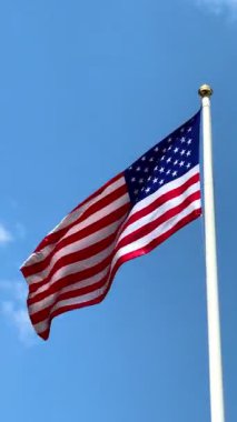 Mavi gökyüzünde büyük bir Amerikan bayrağı dalgalanıyor. Amerikan bayrağı. Amerikan bayrağı. Yüksek 4k kalite video