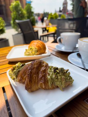 Tahta bir masanın üzerinde bir tabak kruvasanla birlikte beyaz kahve bardağı kapuçino. Kafede kahvaltı, Paris sabahı, Avrupa sabahı. Yüksek kalite fotoğraf