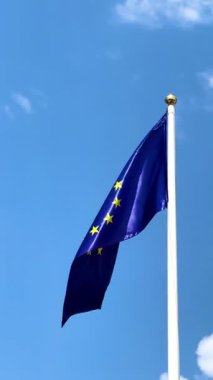Mavi bir gökyüzü ve beyaz bir bayrak direğine karşı dalgalanan büyük bir Avrupa bayrağı. Avrupa Birliği, Avrupa, Avrupa 'daki göçmenler, sığınma, haberler, gazeteler.