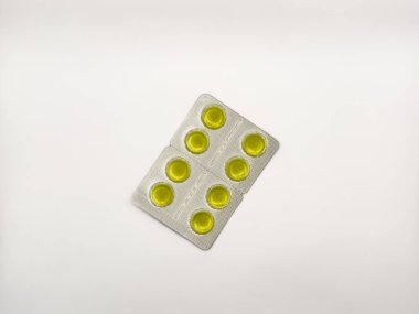 Beyaz arka planda sarı bir hap var. Toplamda altı hap var. Hap görüntünün ortasında, kopyalama alanı, deri döşeme, üst görüş. Yüksek kalite fotoğraf