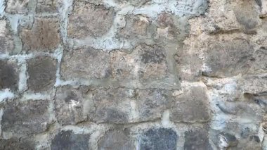 Kaba bir dokusu olan taştan yapılmış bir duvar. Duvar gri ve birkaç çatlağı var.