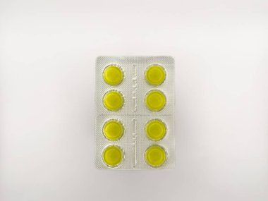 Beyaz arka planda sarı bir hap var. Toplamda altı hap var. Hap görüntünün ortasında, kopyalama alanı, deri döşeme, üst görüş. Yüksek kalite fotoğraf