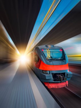 Raylarda bir tren var ve hareket ediyor. Tren kırmızı ve siyah.