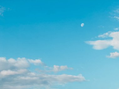 Ay gökyüzünde ışıl ışıl parlıyor, mavi alana gümüş bir parıltı saçıyor. Gökyüzünün ortasında, tüylü beyaz bulutlarla çevrili. Gökyüzü berrak ve lekesiz